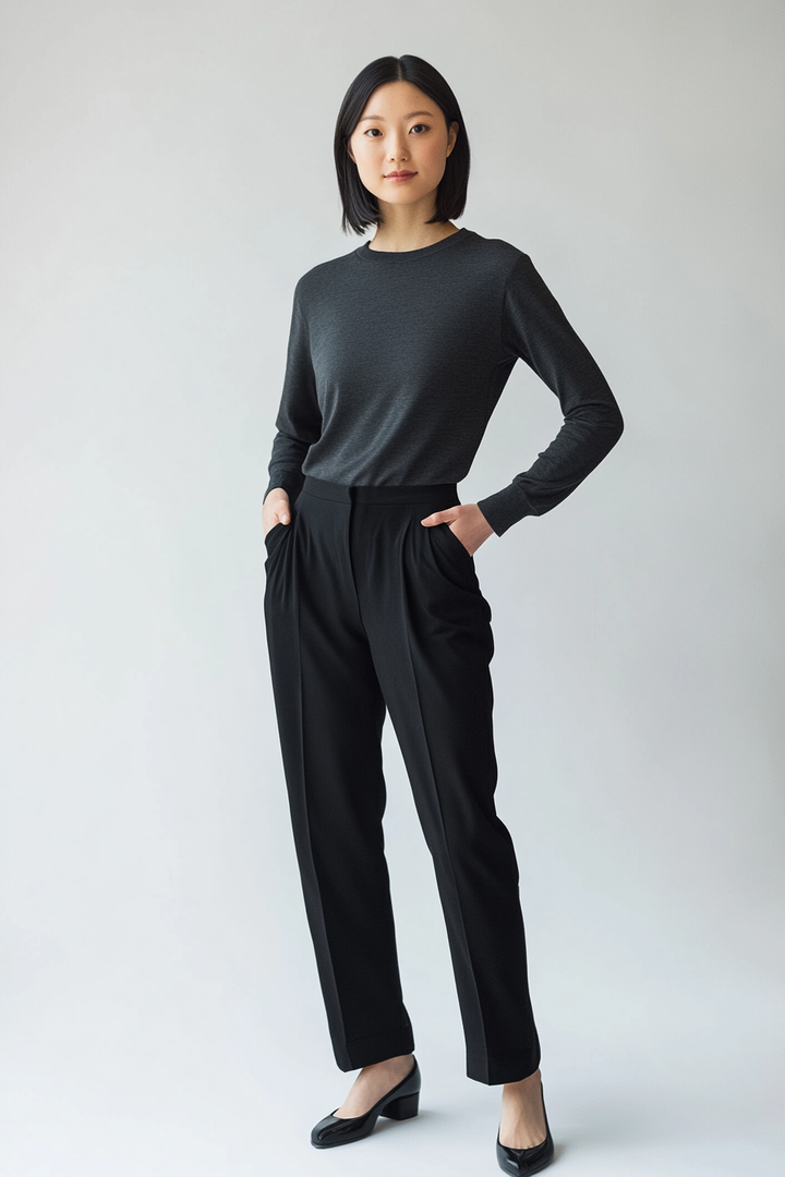Model wearing The Cano Trouser in soft black cotton with a tapered leg and clean ankle-length finish.
