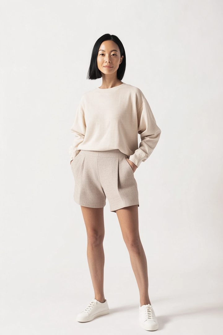 Model wearing The Lido Short in a light oat linen blend with a high-rise fit and soft front pleats.
